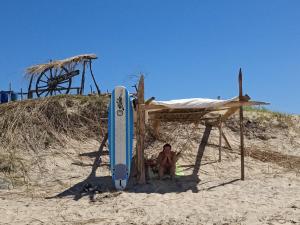 a man sitting in a chair next to a surfboard on the beach at Para un poquito relax in Barra de Valizas