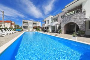 a blue swimming pool in front of a building at Apartments Punta in Privlaka