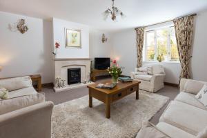 een woonkamer met een tafel en een open haard bij Little Maunditts Cottage - quiet location in charming Cotswold village in Sherston