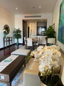 - un salon avec une table et des fleurs blanches dans l'établissement Luxury 1BR apartment in Anantara Hotel Palm Jumeirah connected Anantara Hotel, à Dubaï