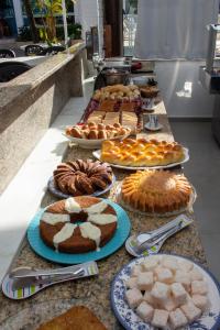 una mesa con muchos tipos diferentes de pasteles y tartas en Pousada Daleste en Angra dos Reis