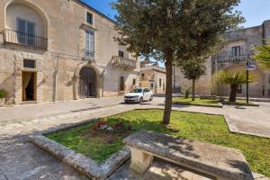 un banco frente a un edificio con un árbol en Le Dimore di Hanqorias, en Muro Leccese