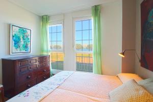 a bedroom with a bed with a dresser and two windows at El Rincón del Puerto in Santander