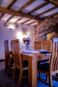una mesa de madera con sillas y un jarrón de flores en Forget me not cottage en Ironbridge