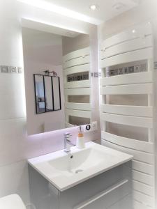 a white bathroom with a sink and a mirror at Les Jardins de la quiétude in Bettancourt-la-Ferrée