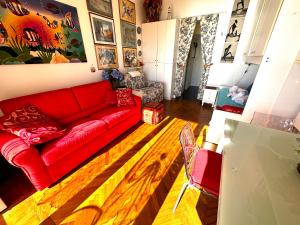 een woonkamer met een rode bank en een houten vloer bij Suite Fronte Mare - Sanremo in Sanremo