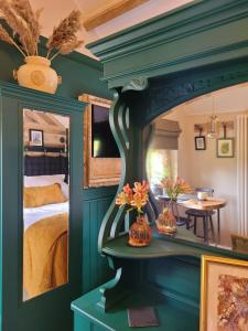a bedroom with a green wall with a mirror and a bed at Kettle Tree Cabin in Welshpool