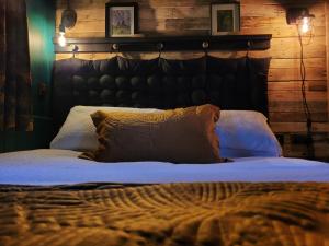 a bedroom with a large bed with a wooden wall at Kettle Tree Cabin in Welshpool