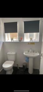 a white bathroom with a toilet and a sink at Mells Shells in Hemsby