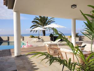 una piscina con sedie, ombrelloni e oceano di Boutique Hotel Colina del Emperador a La Manga del Mar Menor