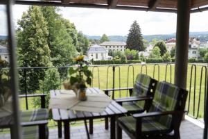 een tafel en stoelen op een balkon met uitzicht op een veld bij Villa Schwertführer in Velden am Wörthersee