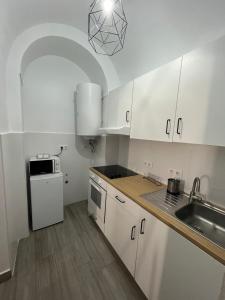 una pequeña cocina con armarios blancos y fregadero en La Sala by Casa de Rosita AT-BA-00215, en Fuente del Maestre