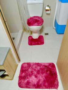 baño con aseo rosa y alfombra rosa en MyrVin at Grass Residences, QC en Manila