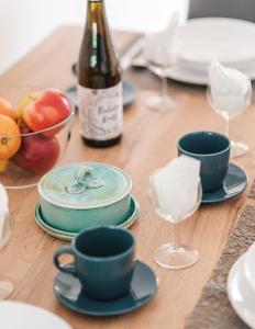 - une table avec des assiettes, des tasses et une bouteille de vin dans l'établissement Tulipános Ház, à Bytom