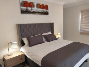 a bedroom with a large bed with two lamps on it at LND GUEST HOUSE in Bloubergstrand