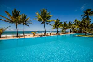 a swimming pool with palm trees and the beach at Vivant Eco Beach OFICIAL in Barra Grande