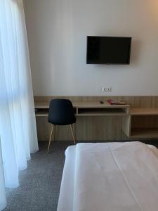 een kamer met een bed, een tv en een stoel bij Bernstein-Motel Marchegg in Marchegg