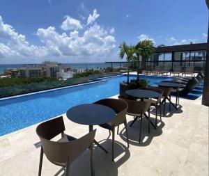 een rij tafels en stoelen naast een zwembad bij Luxury Studios On The 5th avenue Ocean View Rooftop I By Yeah in Playa del Carmen