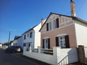 a white and pink house with a fence at Maison au calme, proche centre et mer, jardin clos in Le Croisic