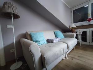 a white couch with blue pillows in a living room at Mansarda Shabby Chic in Fiumalbo