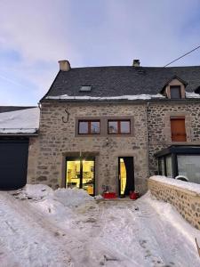 uma casa de pedra com neve em frente em Joli gîte au cœur du Cézallier 3étoiles em Landeyrat