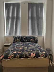 a bedroom with a bed with a floral bedspread and two windows at 2 bedroom city centre apartment 35 Victoria street in Liverpool