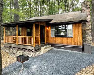 a log cabin with a porch in the woods at Mountain Springs Lake Resort in Stroudsburg