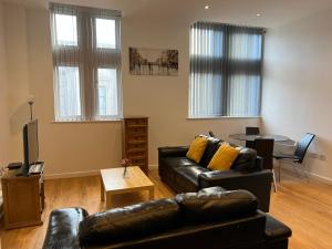 a living room with a black leather couch and a table at 2 bedroom city centre apartment 35 Victoria street in Liverpool
