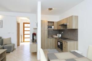 a kitchen with wooden cabinets and a living room at Apartments Punta in Privlaka