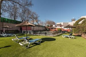 un gruppo di sedie e ombrelloni sull'erba di Hotel Rio Badajoz a Badajoz