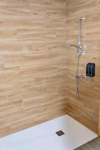 La salle de bains est pourvue d'une douche et d'un mur en bois. dans l'établissement Apartamentos El Mirador de la Janda, à Benalup-Casas Viejas