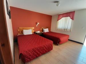 two beds in a hotel room with red walls at Hotel y Restaurante Villa Esmeralda in Quetzaltenango