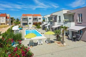 a courtyard with a pool and chairs and umbrellas at Apartments Punta in Privlaka