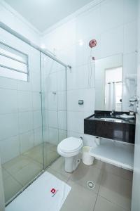 uma casa de banho com um WC e uma cabina de duche em vidro. em Expo Hotel em São Paulo