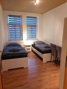 two beds in a room with two windows at FeWo Nina 2 - Monteurwohnung in Weißenfels