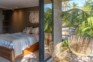 a bedroom with a bed and a balcony with chairs at Fishermans Resort Life in La Libertad