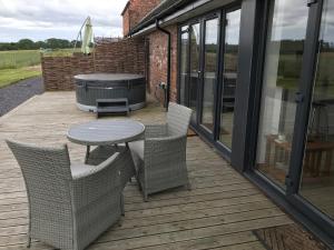 a patio with a table and chairs and a grill at The Stables and Granary at Shawbroom Farm in Cheswardine
