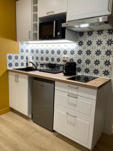 una cocina con armarios blancos y azulejos blancos y negros en Superbe Studio Meublé - Houdan, en Houdan