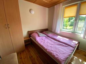 małe łóżko w pokoju z oknem w obiekcie Domek z prywatną plażą w mieście Radzyń