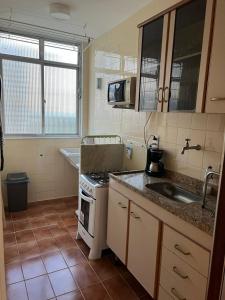 una pequeña cocina con fogones y fregadero en Apartamento Temporada Barra da Tijuca, en Río de Janeiro