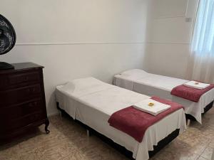 a room with two beds and a dresser and a dresser at Apartamento Temporada Barra da Tijuca in Rio de Janeiro