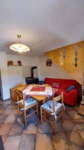 a living room with a table and a red couch at Maso Brunetto in Canale San Bovo