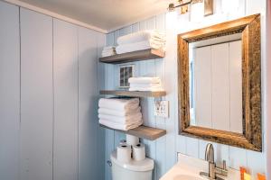 La salle de bains est pourvue d'un lavabo, d'un miroir et de serviettes. dans l'établissement Charming Tiny Cottage with Boat Dock on Crooked Lake, 