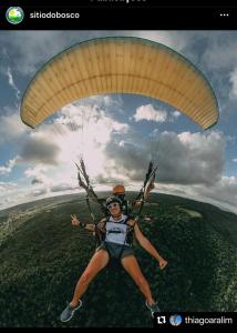 a woman is holding onto a parachute at Sítio do Bosco Park in Tianguá