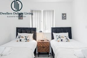 2 Betten in einem Schlafzimmer mit einem Nachttisch dazwischen in der Unterkunft Dwellers Delight Living Ltd Serviced Accommodation Charming 3 Bedroom Flat, Chafford Hundred, Grays with Free Parking & Wifi in West Thurrock