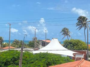 uma tenda branca com palmeiras e o oceano em Maria Flor Pousada em Taíba