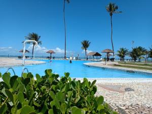 a swimming pool on the beach with palm trees at Village Galés de Maragogi in Maragogi