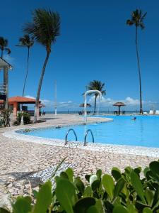 a swimming pool with palm trees on a beach at Village Galés de Maragogi in Maragogi