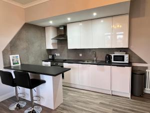 a kitchen with white cabinets and a black counter top at Castle Grant Apartment in Inverness +8 photos