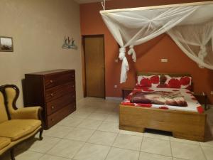 ein Schlafzimmer mit einem Bett, einem Stuhl und einer Kommode in der Unterkunft AUBERGE LA PRALINE 